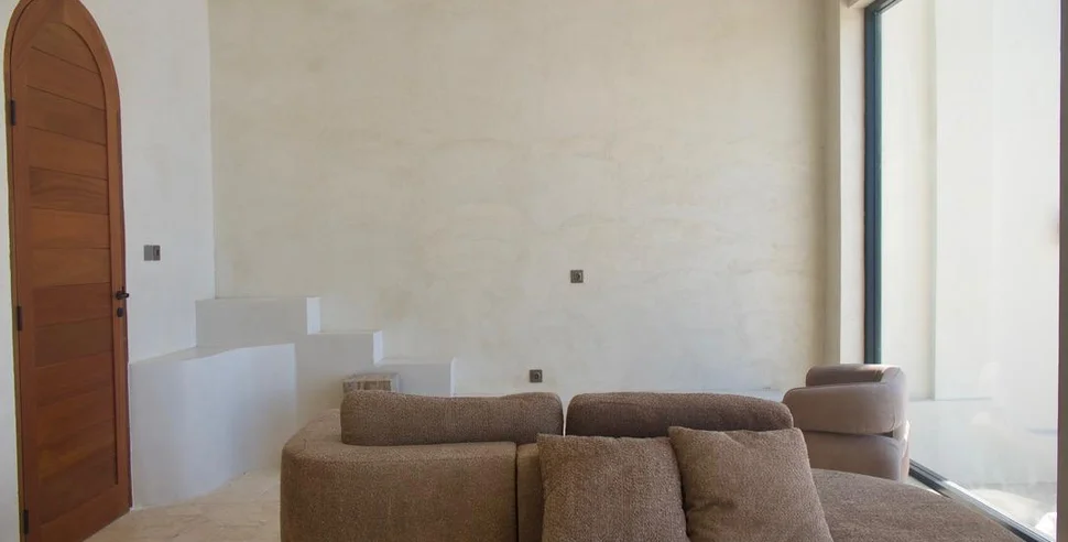 A living space with microcement walls and floor running unbroken between rooms.