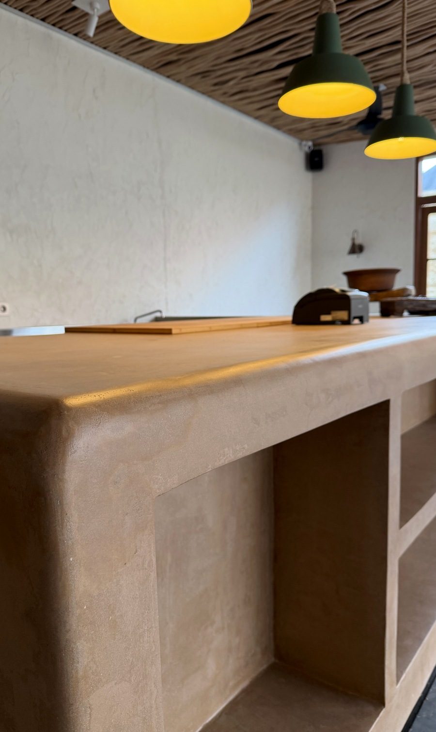 A kitchen island finished in Microcement X, with a seamless surface running over the edge.
